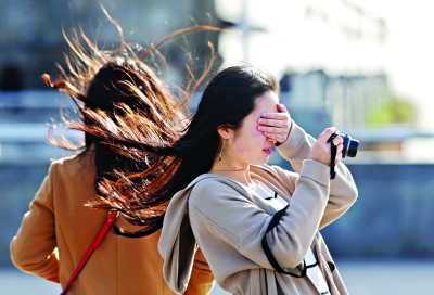 一名女生在汉口江边被风吹得睁不开眼 记者任勇 摄