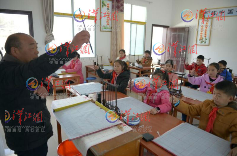 书法教师王先知在教学生们拿毛笔的正确姿势。