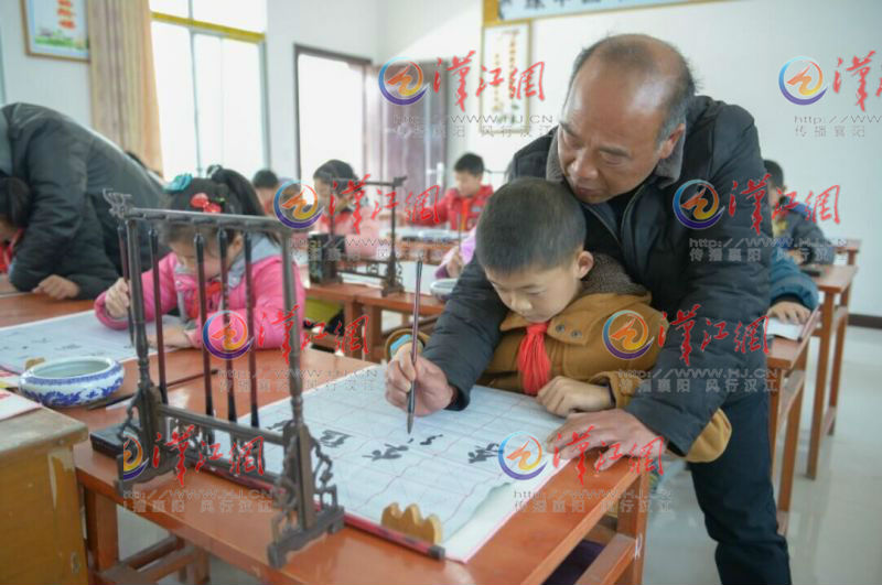 王老师手把手教学生写书法。