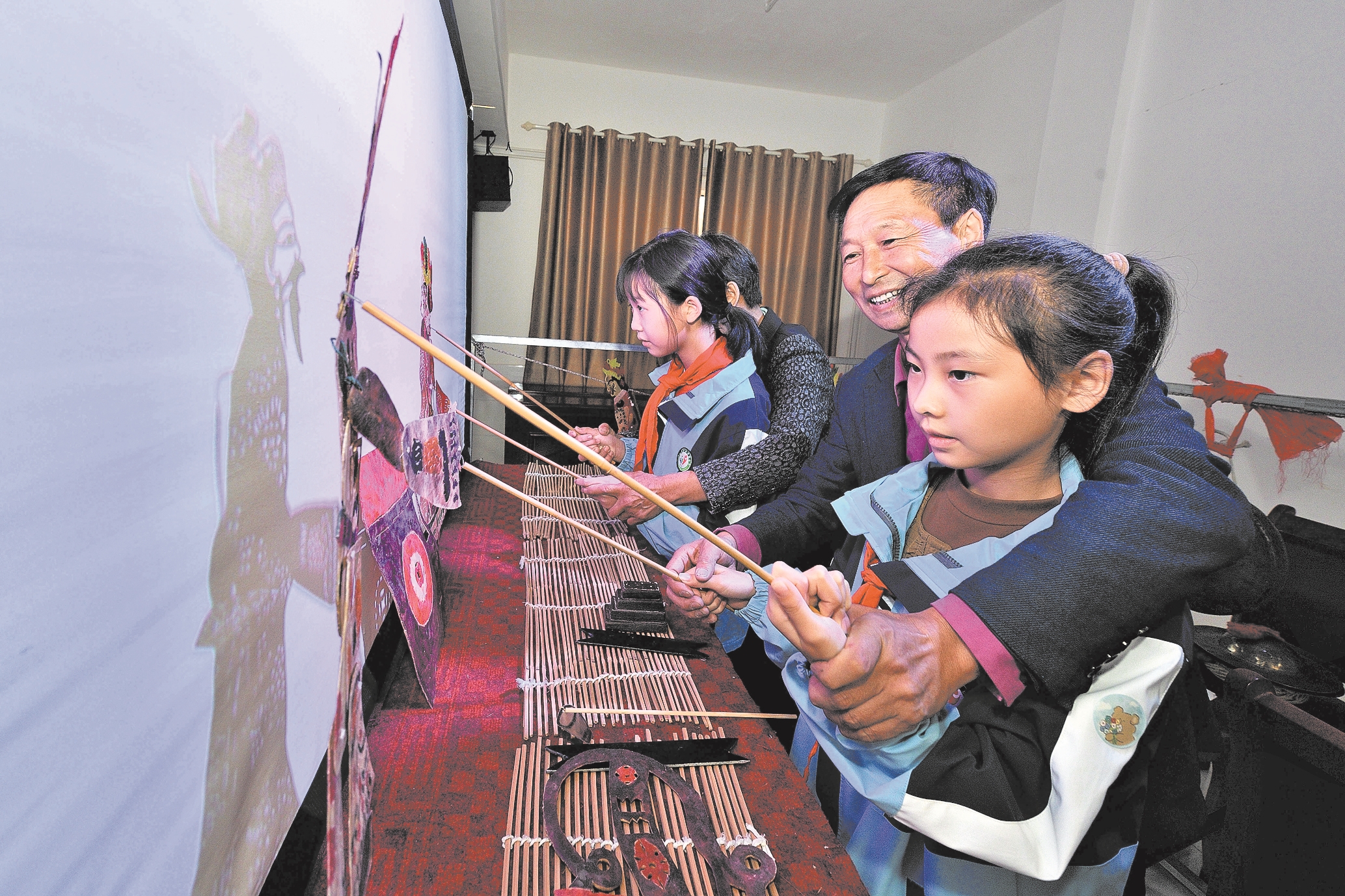 10月8日,在保康县店垭镇小学,民间皮影艺人手把手指导学生表演皮影戏.