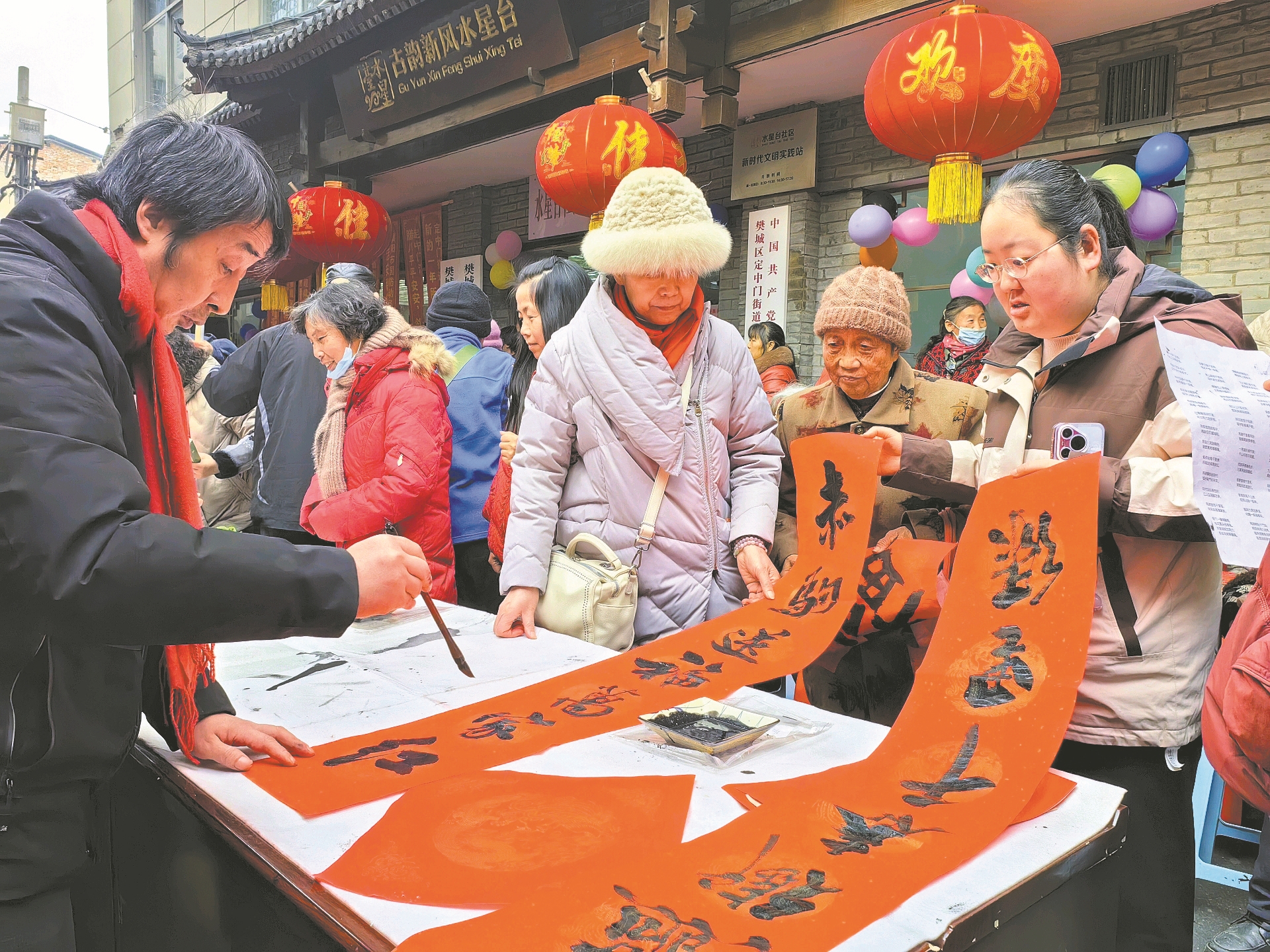 ↑1月26日,樊城区水星台社区举办“红联送万福 香粥暖千家”第十五届腊八赶集会,邀请居民共聚一堂,红红火火过腊八节。图为书法家为居民写春联。 全媒体记者 谢勇 通讯员 张沛 摄