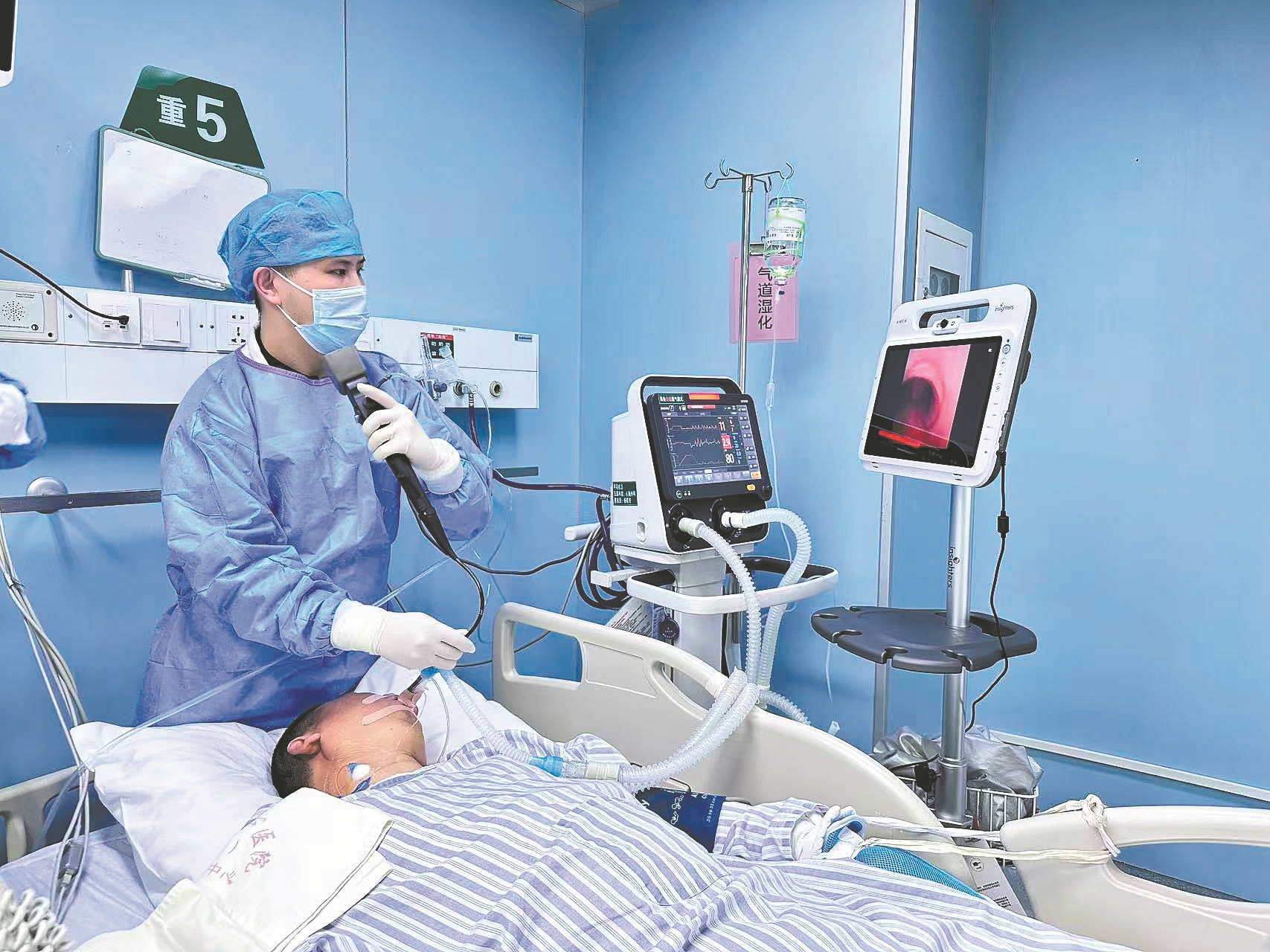 呼吸治疗师行床旁纤支镜治疗。