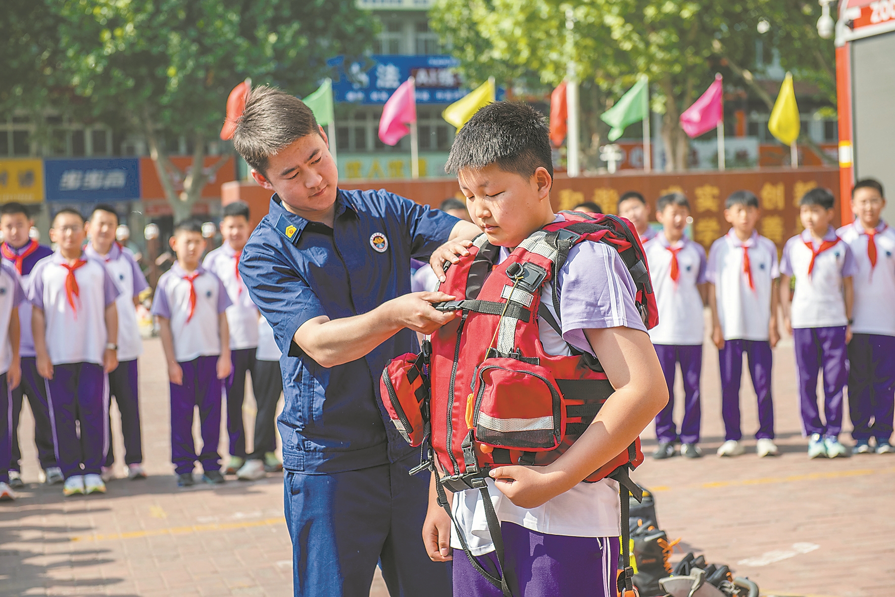 5月12日,河北省遵化市第一实验小学的学生在消防救援人员的帮助下体验救生衣穿戴。 新华社 发