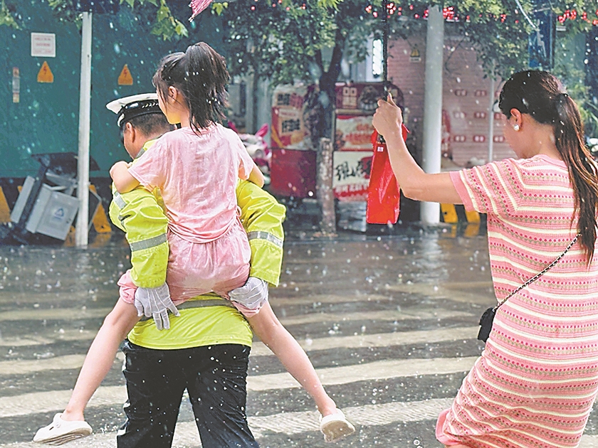 8月12日,在樊城区人民路与风华路交叉口,执勤民警背着一名小女孩蹚过积水的人行横道。记者 李旭晖 通讯员 张然然 赵少华 摄
