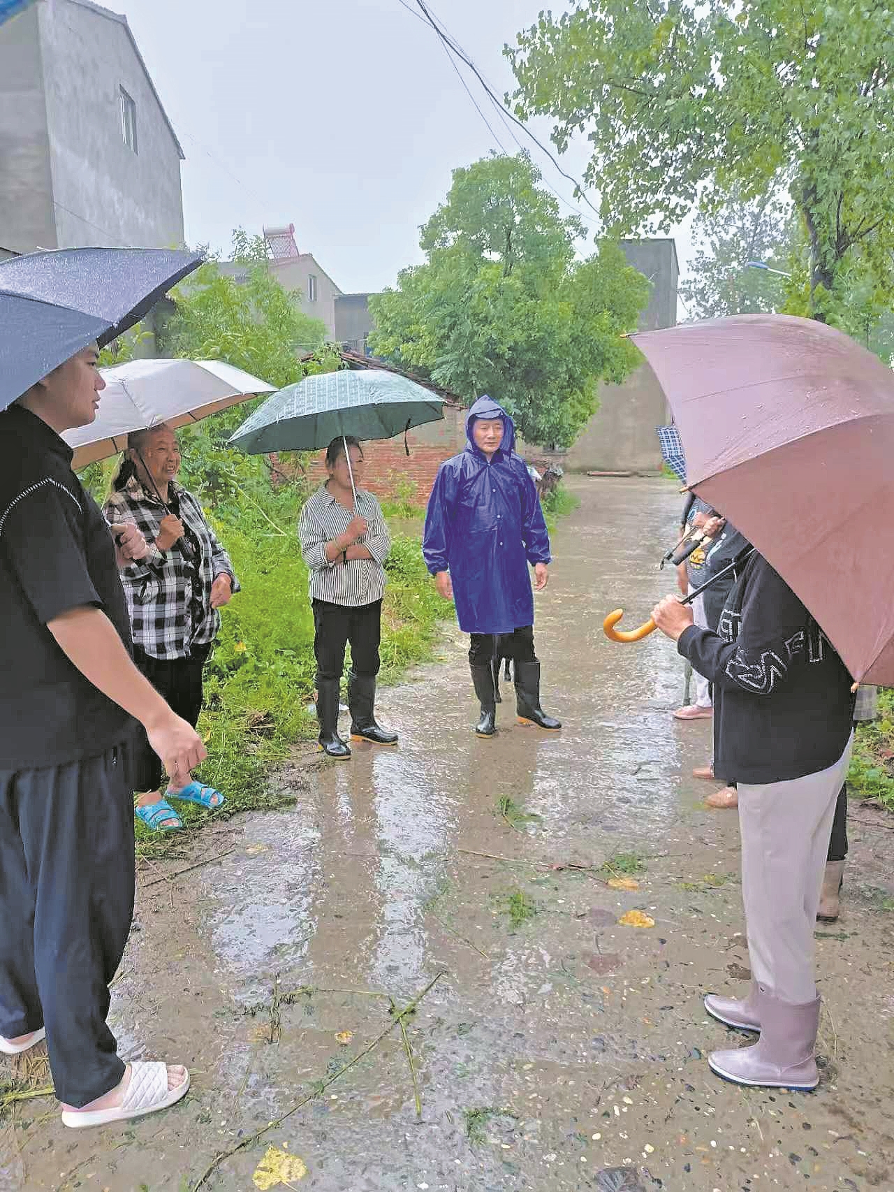 陈虎(穿雨衣者)耐心做村民思想工作。记者 孙建娇 汪岩岩 摄